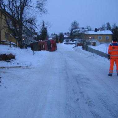 Lastebil veltet med fult lass i en avkjørsel i en bakke